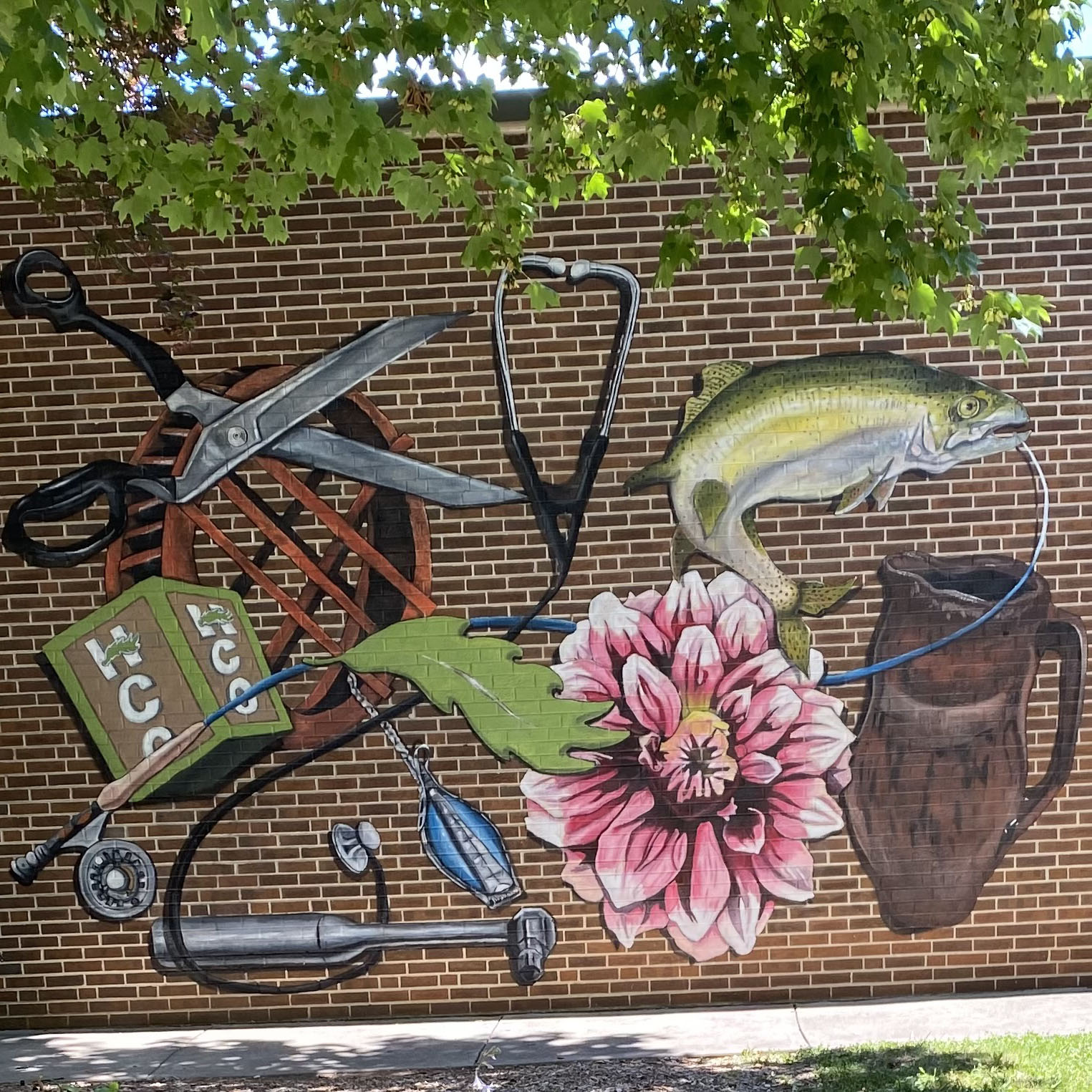 painted mural on brick with multiple images such as scissors, fish, flowers, and stethoscope